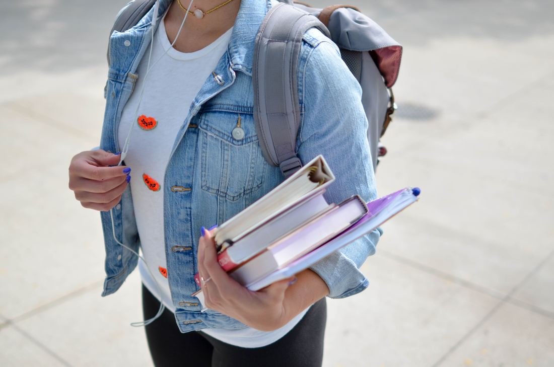 Female student wearing a backpack and holding books
